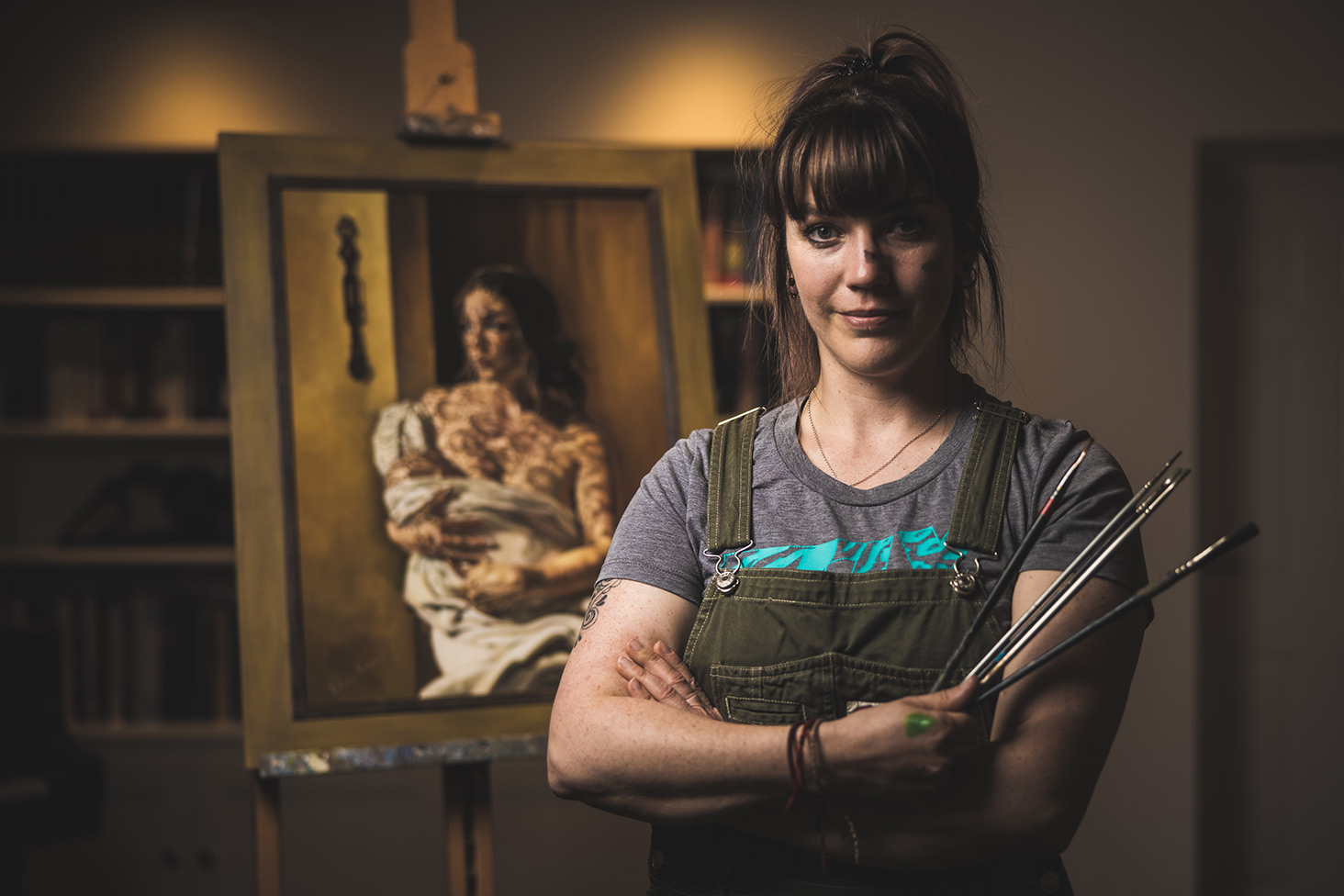 Elin Sian Blake standing next to easel holding paint brushes