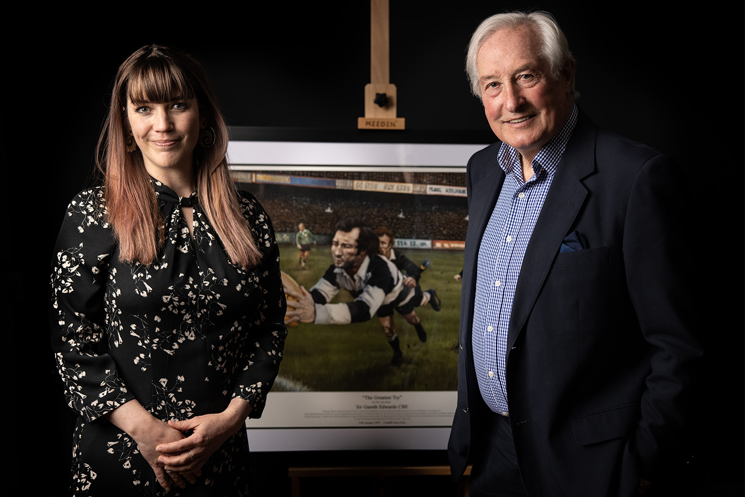 Gareth Edwards and Elin Sian Blake standing with The Greatest Try framed print on easel